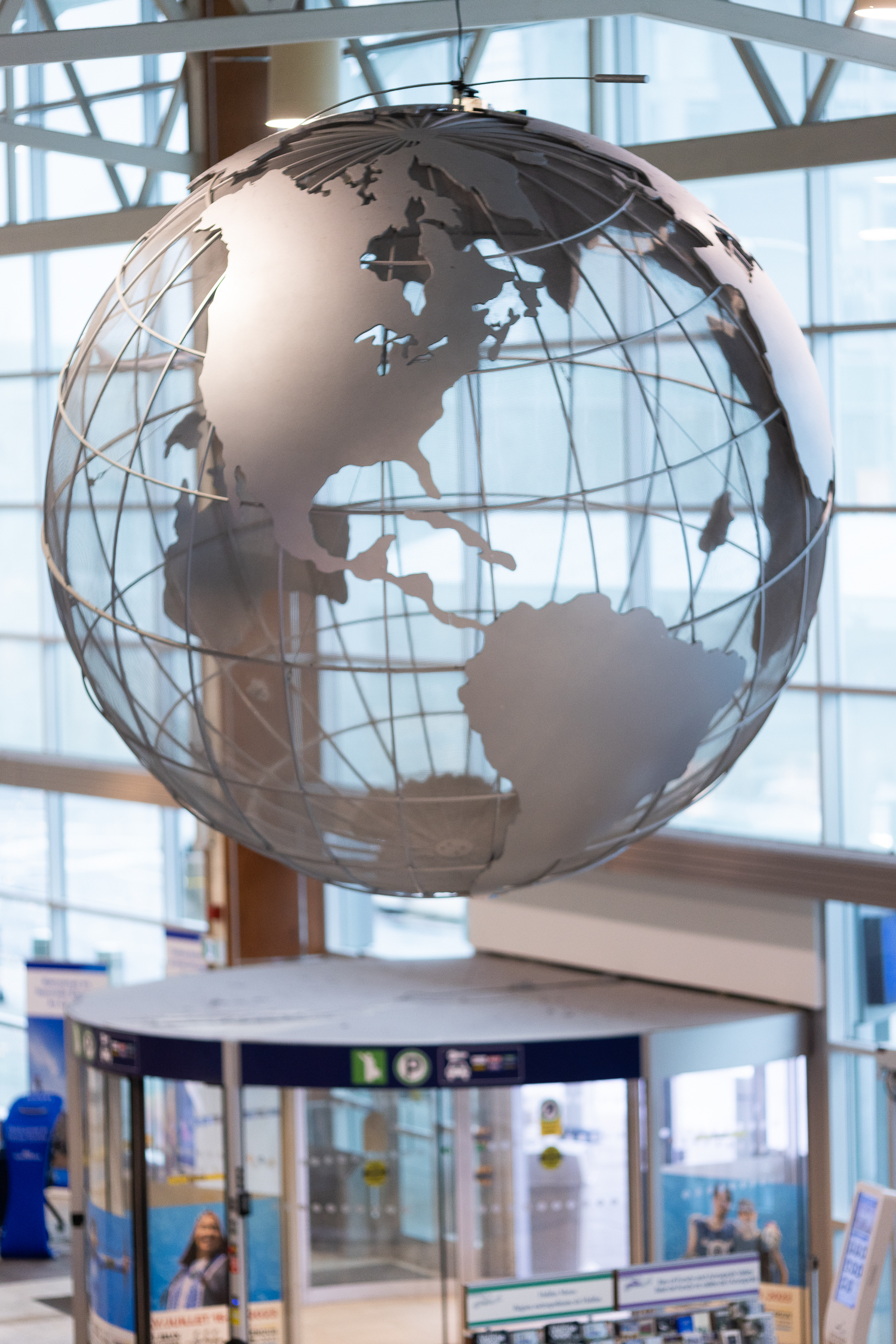 A metal/wire artistic globe hanging from the airport ceiling