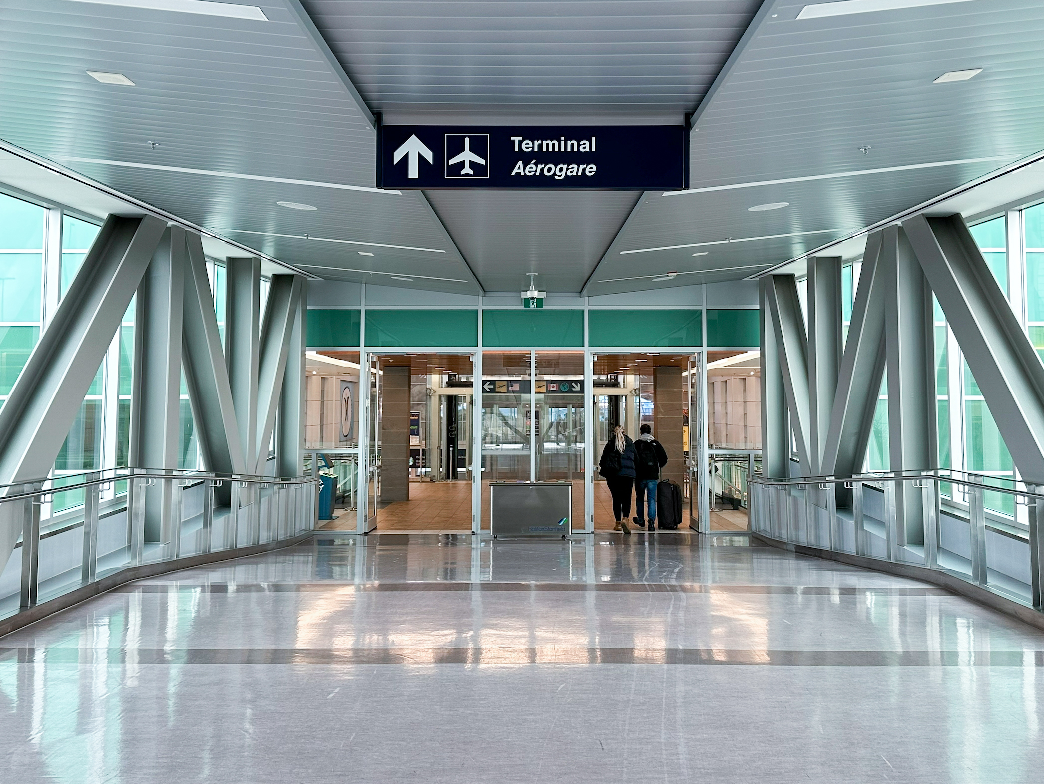 Une passerelle avec des panneaux indiquant aux personnes comment se rendre au terminal de l'aéroport